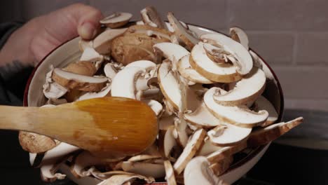 cocinar hongos - verter rebanadas de hongos en la sartén con una cuchara de madera