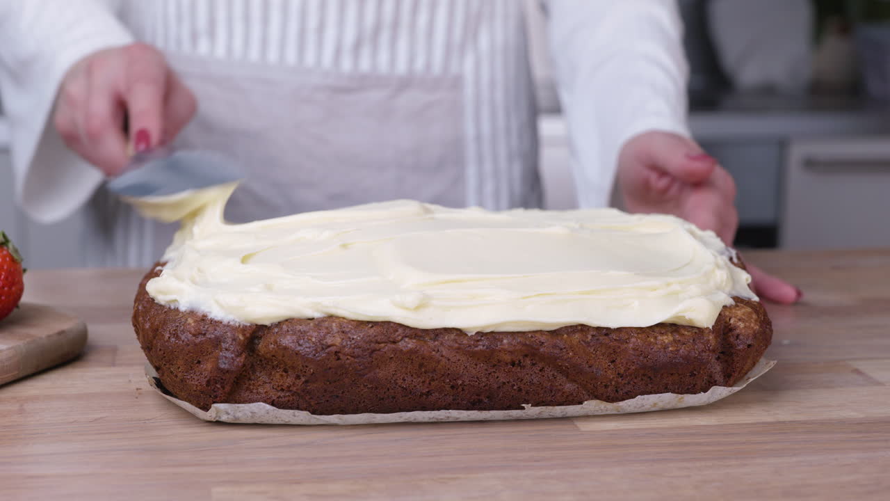 Female Baker Spreading White Frosting on Carrot Cake with Spatula