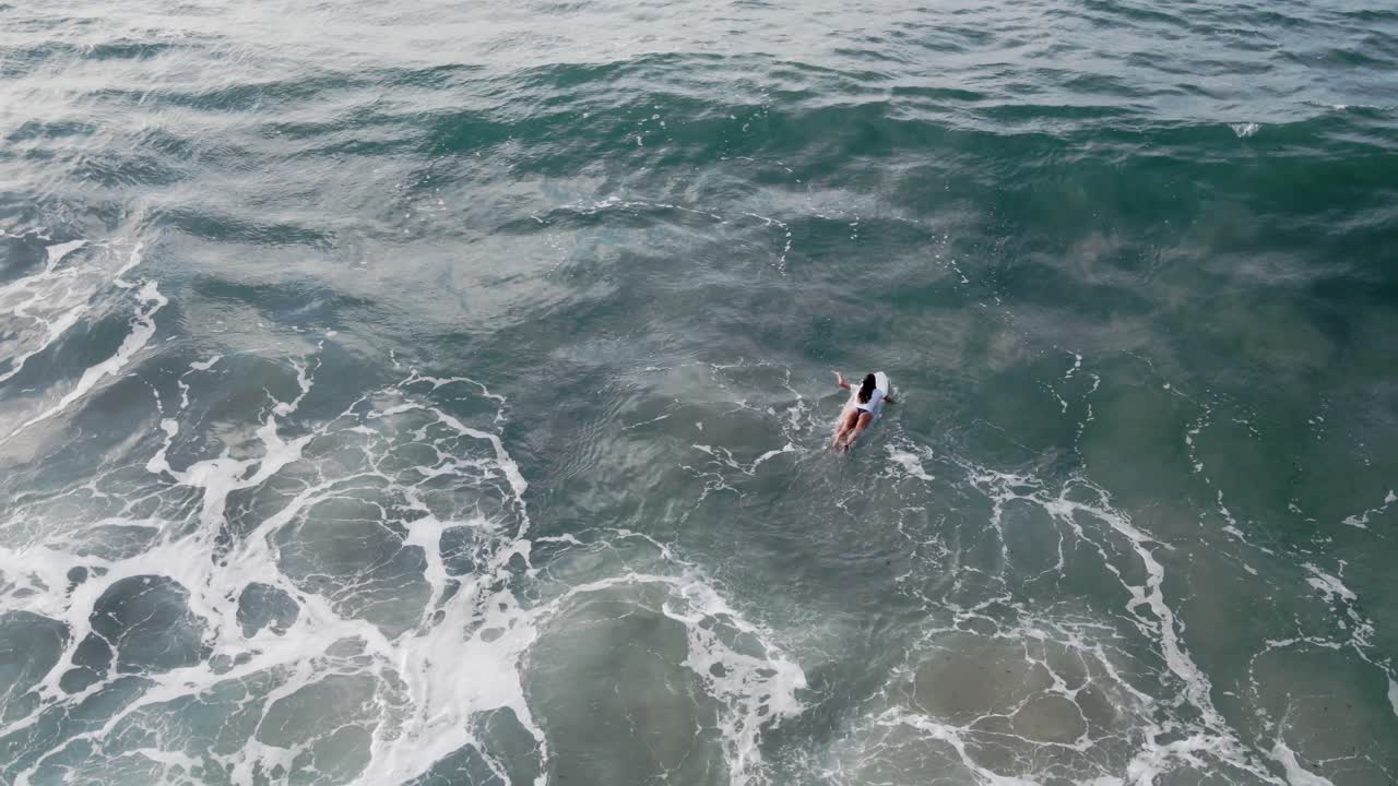 mujer joven en bikini está surfeando en el mar en israel, playa netanya