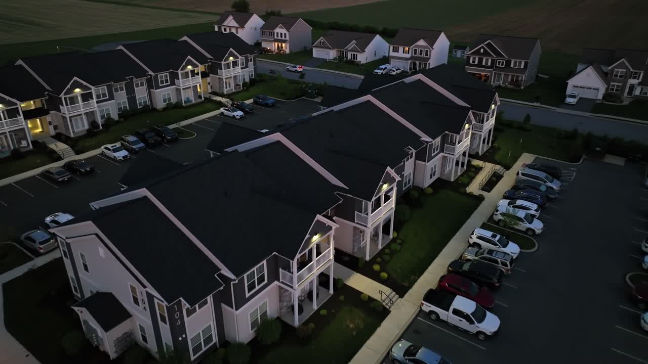 Row of modern apartment buildings with parking cars at dusk. Aerial top down flyover shot. Night scene in american neighborhood. Quiet scene in suburbia.