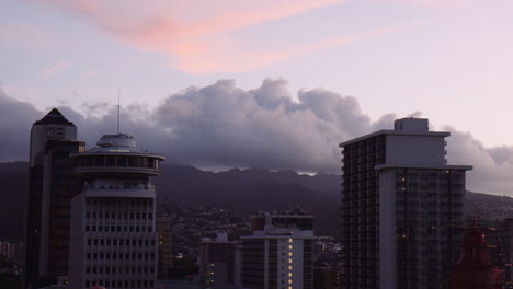 Cimas-De-Edificios-De-Gran-Altura-Hacia-El-Centro-De-Waikiki-Al-Amanecer-Con-Montañas-En-El-Fondo,-Hawaii,-De-Mano