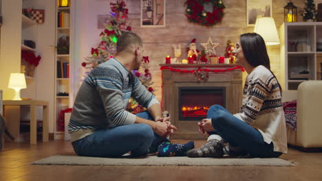 Beautiful-young-couple-looking-at-each-other-sitting-on-the-carpet