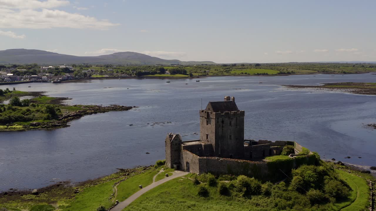 Aerial orbit of Dunguaire Castle, shot reveals Kinvara town in background