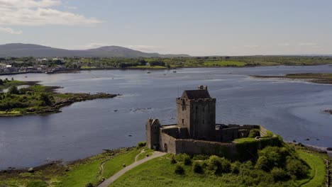 Aerial-orbit-of-Dunguaire-Castle,-shot-reveals-Kinvara-town-in-background