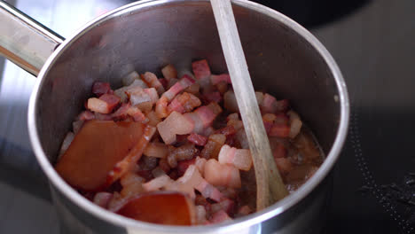 frying thick cut bacon on the pan on electric stove in the kitchen