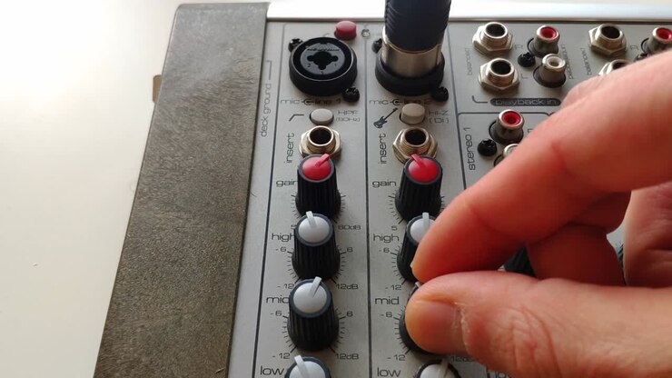 Microphone cable being connected with XLR connector to a mixing desk channel input and the equalizer knobs are turned