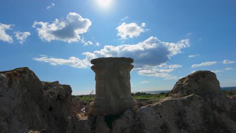 una base de columna solitaria se encuentra en medio de las extensas ruinas bajo un cielo azul brillante, destacando los restos de la arquitectura clásica