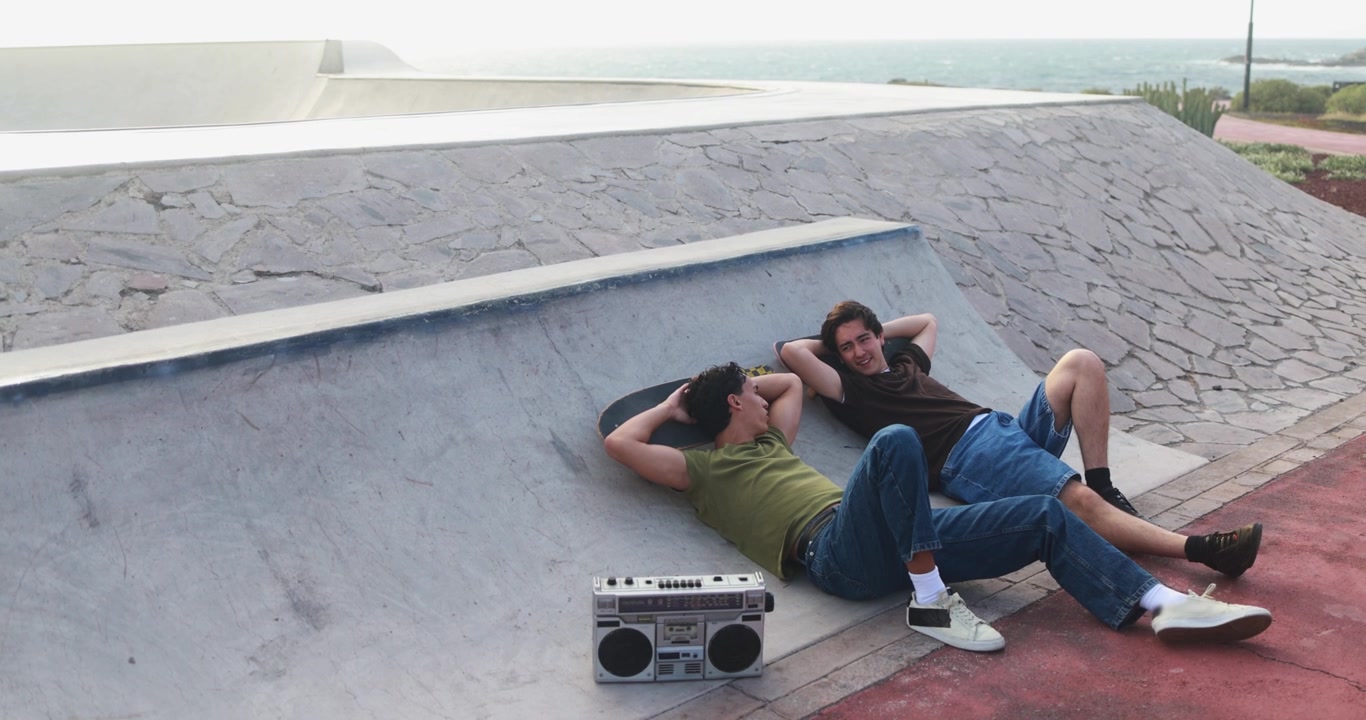 Two Young Men Relaxing at a Skatepark with a Boombox