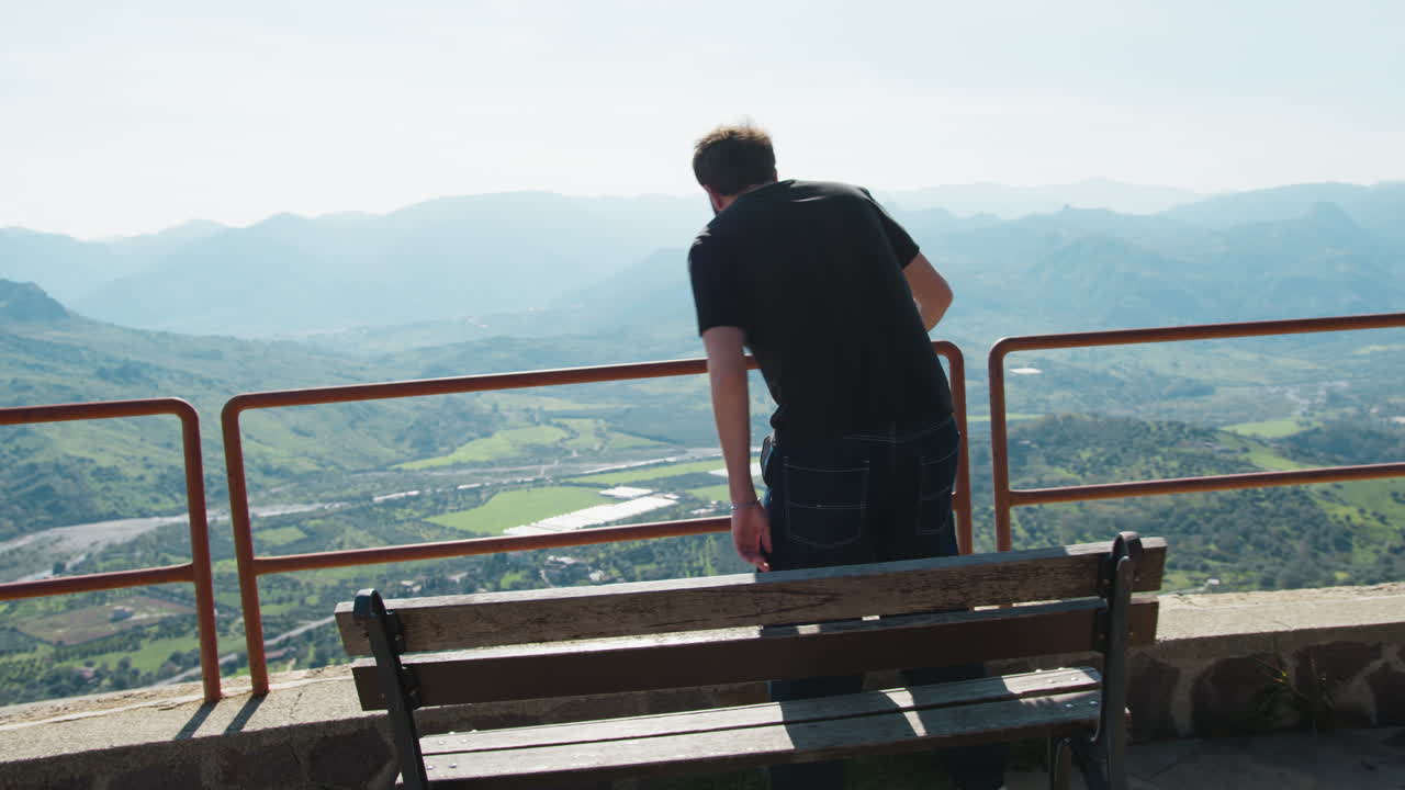 Man Looking at Scenic Mountain View from a Wooden Bench