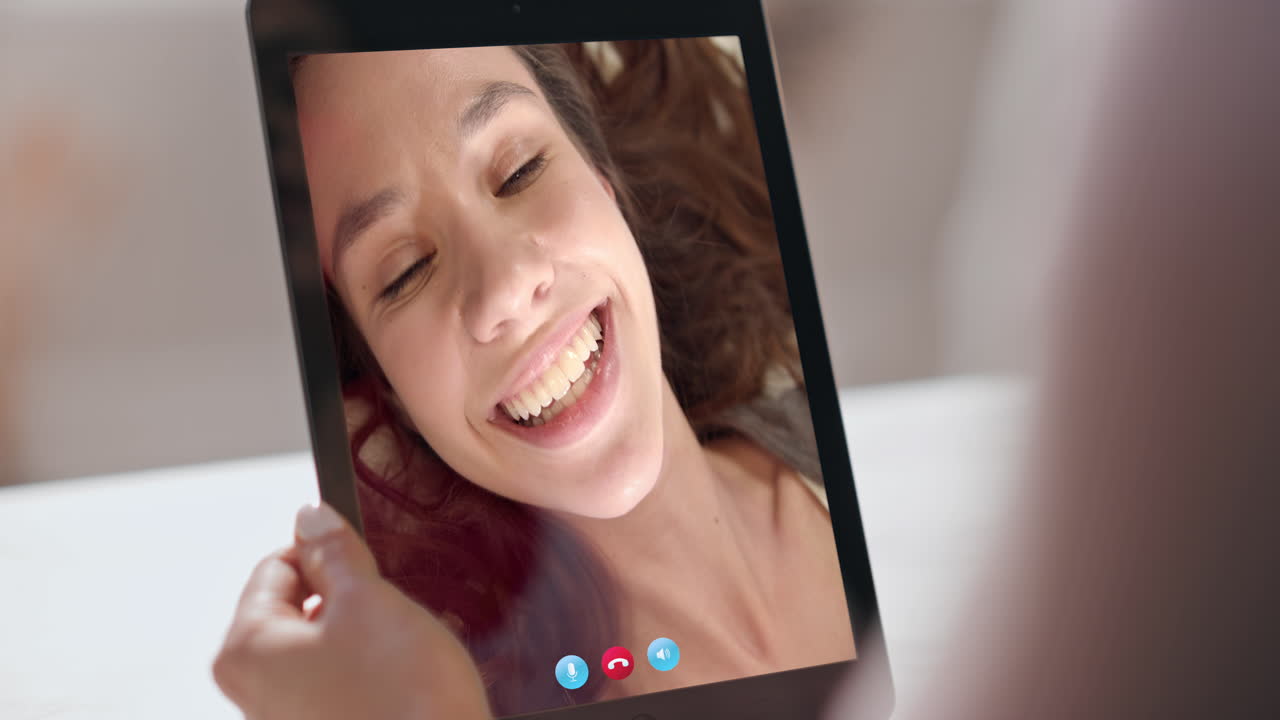 Chattende tieners thuis online via een tablet. Close-up van een hand die een tablet vasthoudt voor een videogesprek