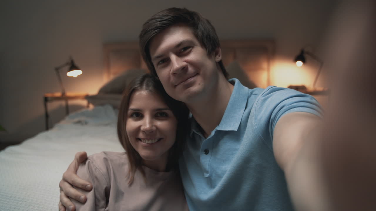 Giovane coppia che si fa un selfie in camera da letto, donna e uomo che condividono momenti