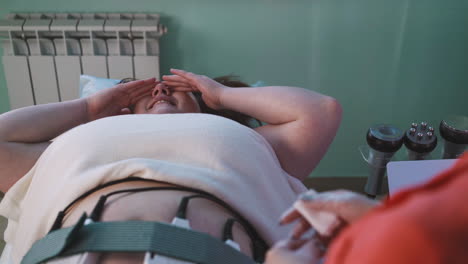 girl with overweight at electrical myostimulation procedure