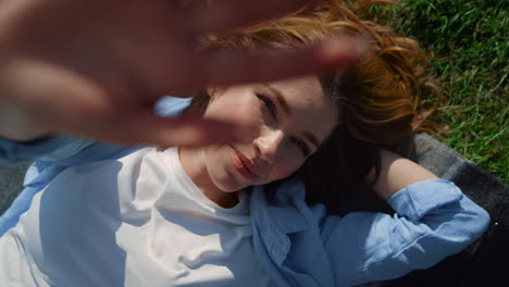 Portrait-of-playful-woman-covering-face-from-bright-sun-beams-in-spring-meadow.