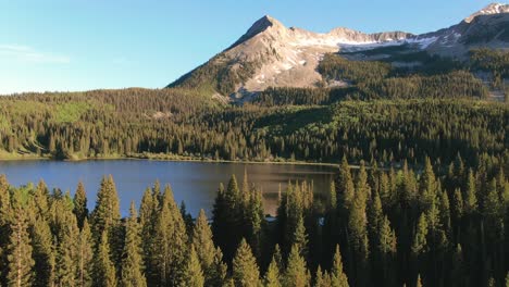 drone flying over pine trees revealing lake near kebler pass mountains in colorado usa