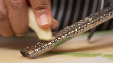 black hands grating ginger to use as an ingredient in a savory dish - isolated close up