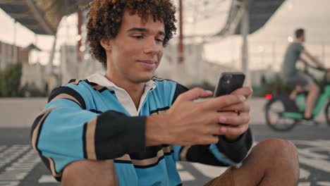 young teen chatting cellphone outdoors closeup. curly guy communicating mobile