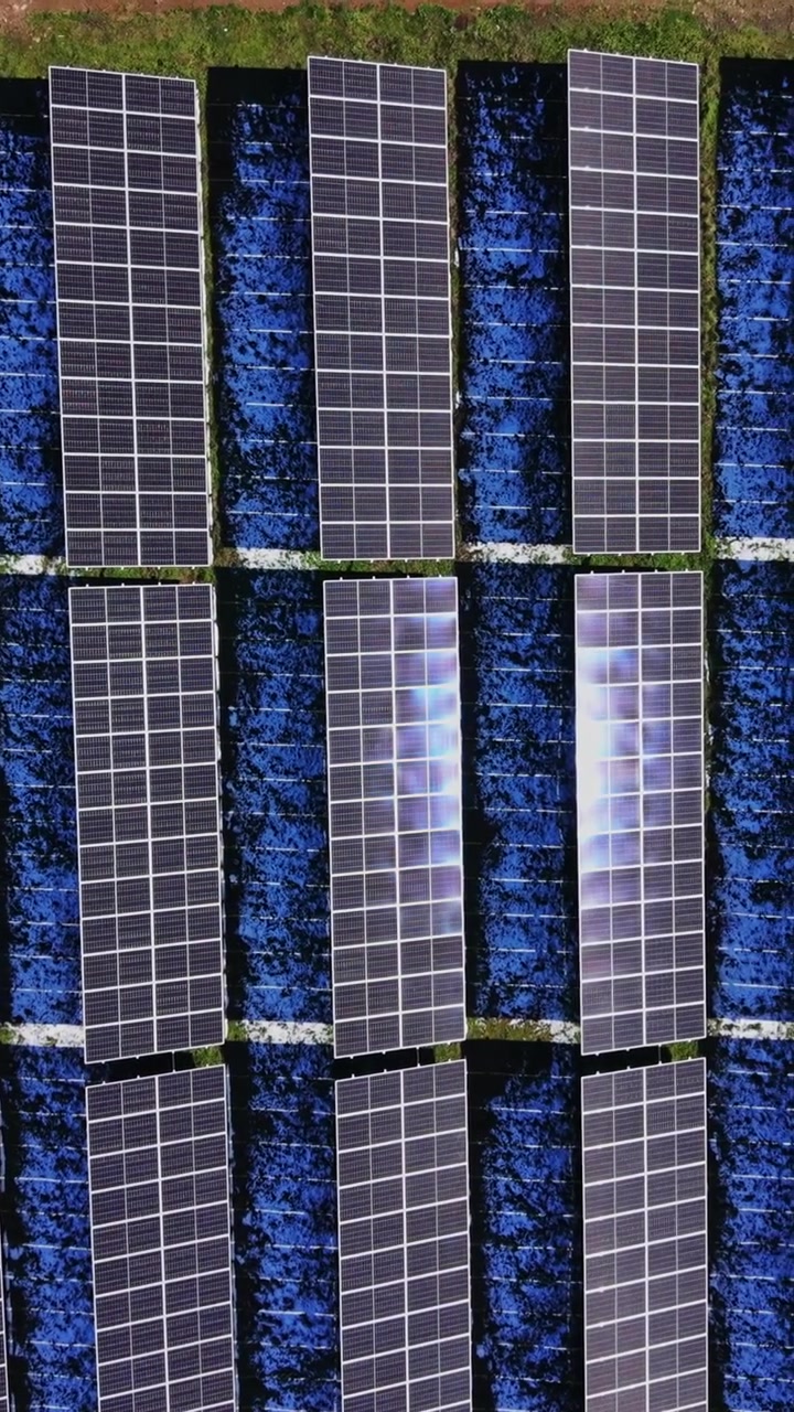 Pannelli solari installati in un campo vicino a una città alla luce del pomeriggio.