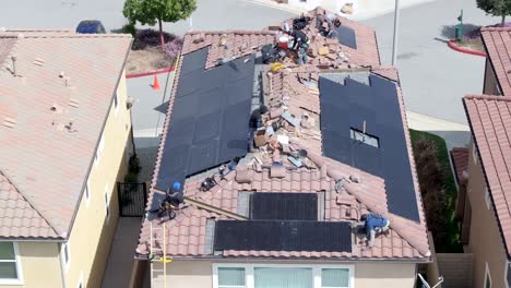 construction crew working on a house roof during a solar panel installation, aerial shot.