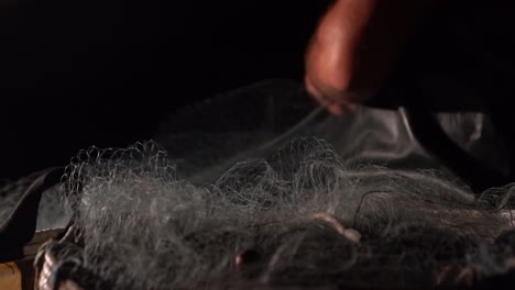 Close-up-of-a-fisherman-pulling-in-the-fishing-nets-on-the-boat-at-night