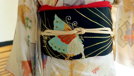 a woman putting on a traditional japanese kimono for a woman in an old traditional japanese house