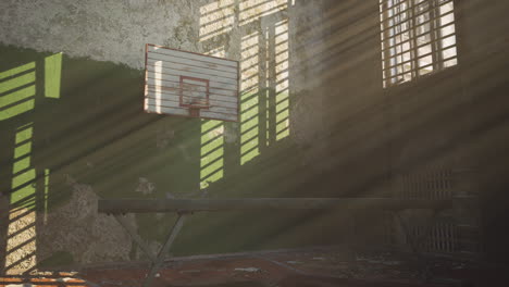 abandoned gym with worn basketball court and sunlight streaming in