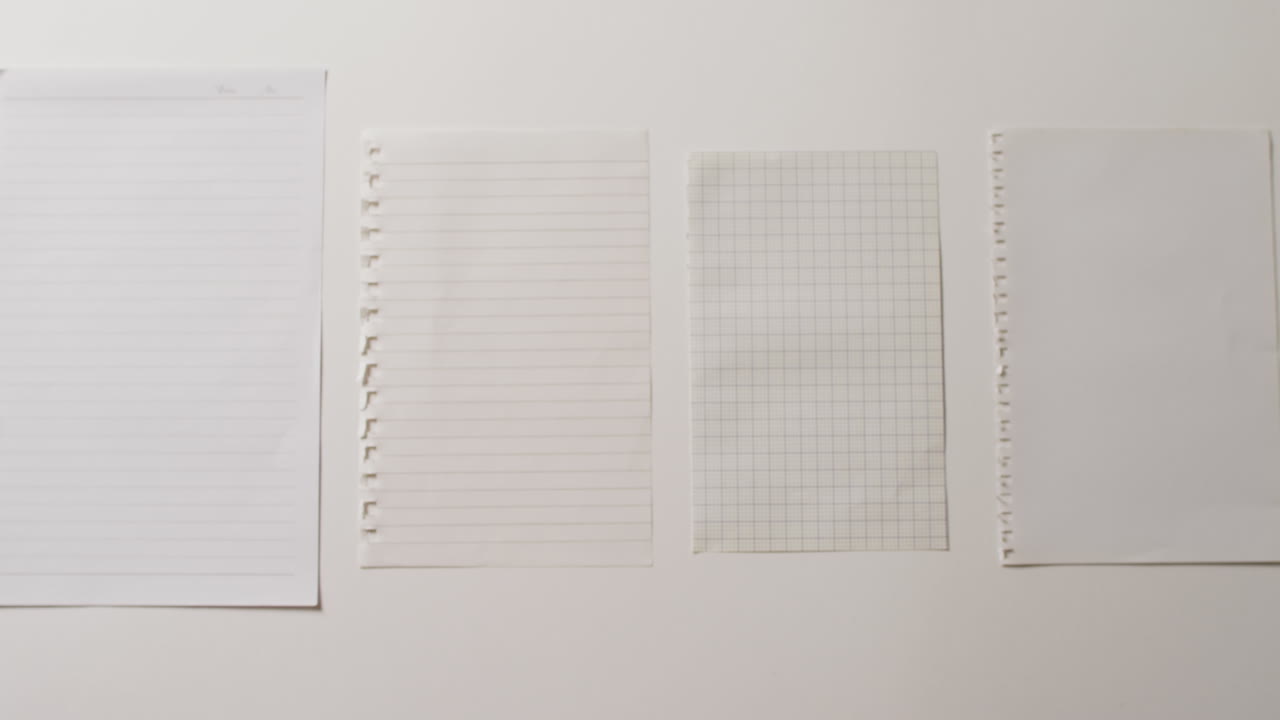 Video of close up of four sheets of notebook paper on white background