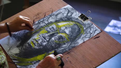 Elderly-Caucasian-women-is-drawing-portrait-of-mysterious-men-wearing-glasses-using-black-and-yellow-charcoal-only-paper-wearing-cinematic-atmosphere-in-dark-room-light-from-outside-close-up-hands