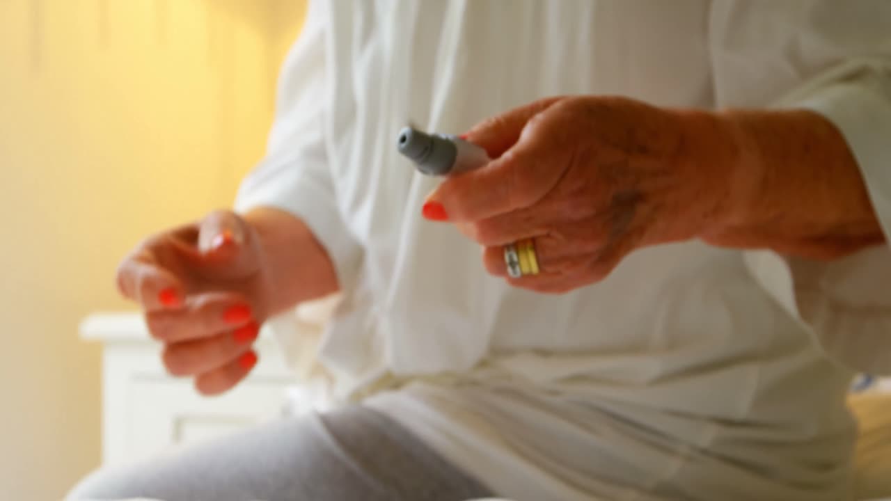 안락한 집에서 혈당 수치를 확인하는 포도당 측정기를 가진 고령 여성의 클로즈업 4k