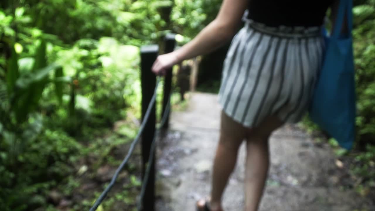 숲길에서 계단을 내려가는 동안 레일을 잡고 있는 숙녀의 슬로우 모션