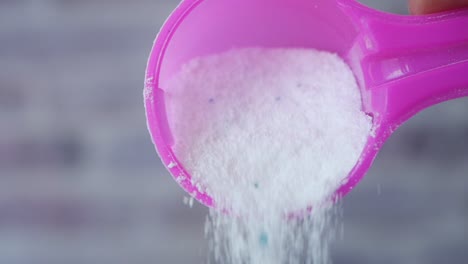 close up of a scoop of laundry detergent being poured out