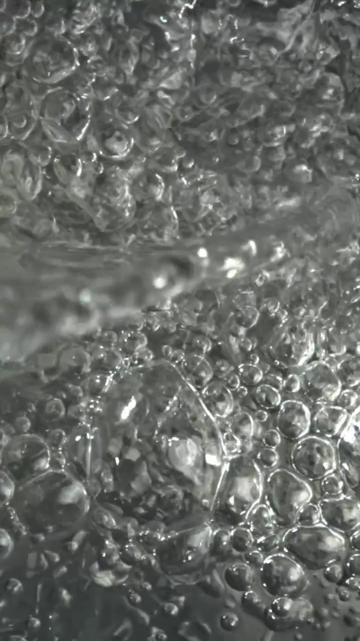 Primo piano dinamico dell'acqua che bolle con molte bolle