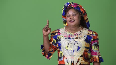 overweight beautiful african woman wearing traditional clothing against green background