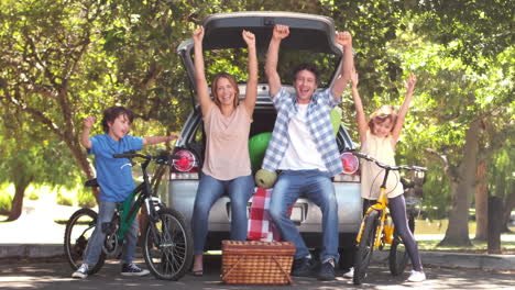 familia feliz delante de un coche con bicicleta