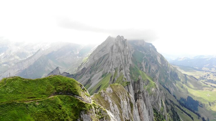 Aerial flyover over the cliffs of Schafler ridge in Appenzell, Switzerland towards Altenturm peak on a cloudy summer day with a view of one of Switzerland's most popular, yet dangerous hiking trails-1