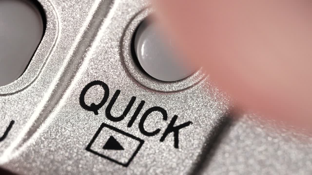 Macro view of Quick button pressed on metallic silver panel with black lettering