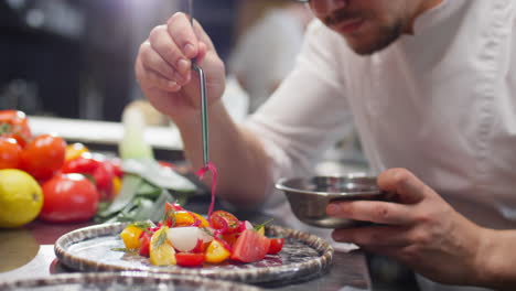 chef putting pickled onion on top of salad