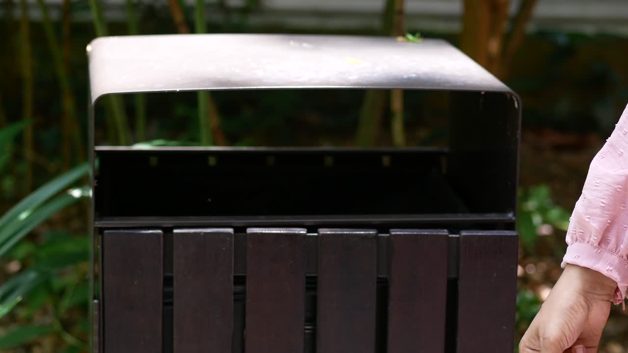 여성이 쓰레기통에 플라스틱 패을 던지는 모습