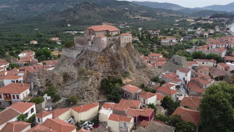 drone circles around virgin mary greek orthodox church at top of rock surrounding old petra village on aegean sea with olive groves garden and mountains in the background, lesbos island