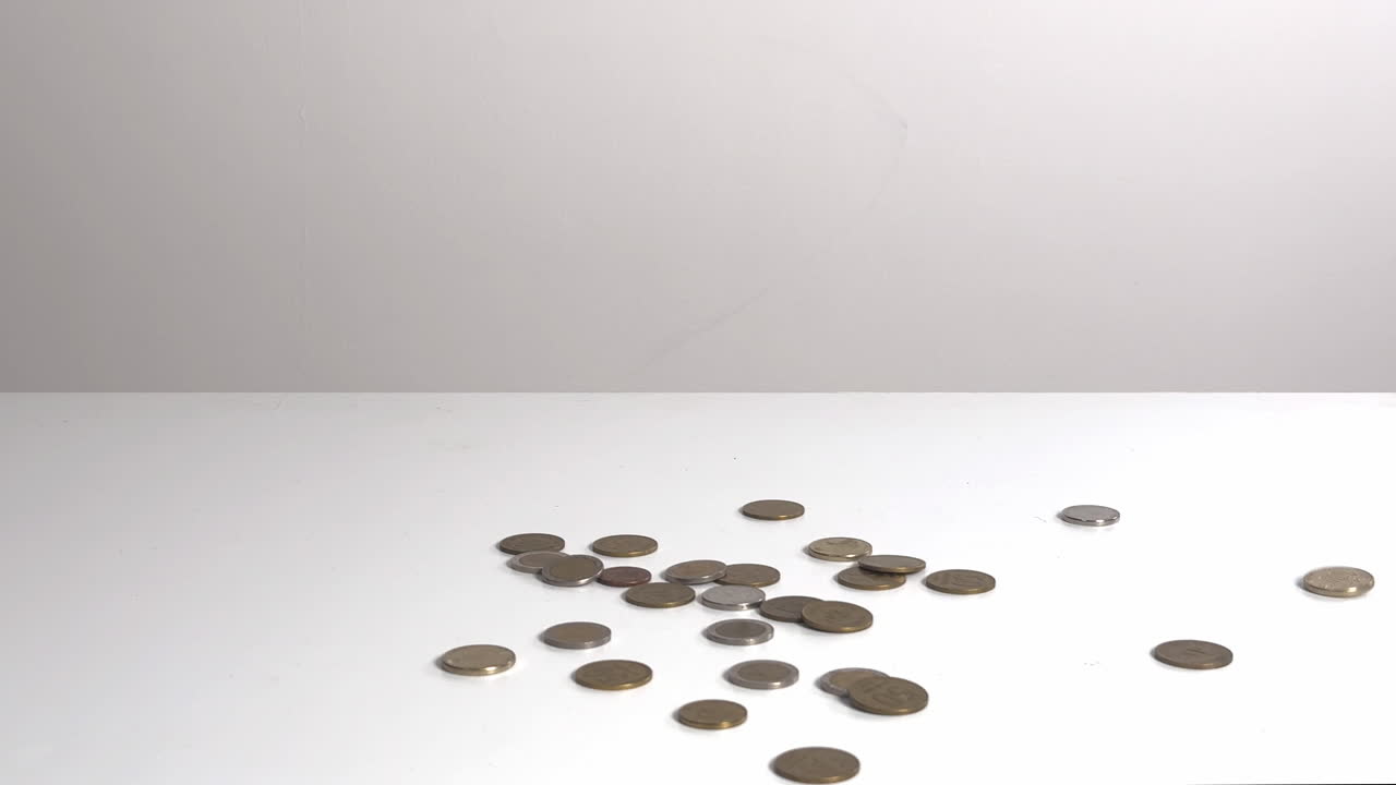 Hand Dropping Coins onto a White Surface
