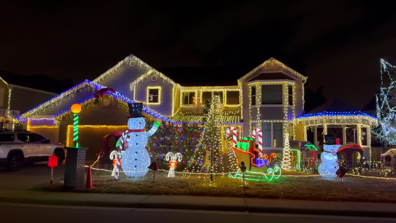 스노우맨 산타클로스 하우스 크리스마스 트리 행복한 휴일 장식 하이랜드 랜치 덴버 콜로라도 미국 밤 시간 밝은 활기찬 불빛 집에 매달린 이웃 느린 팬 오른쪽 모션
