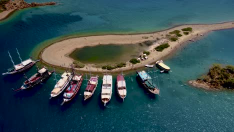 drone capturing the vintage boats docked adjutant to the small island in the sea with blue waters