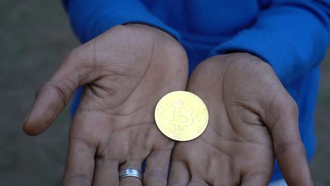 Close-up-shot-of-dirty-bitcoin-cryptocurrency-gold-in-the-hands-of-an-dirty-man