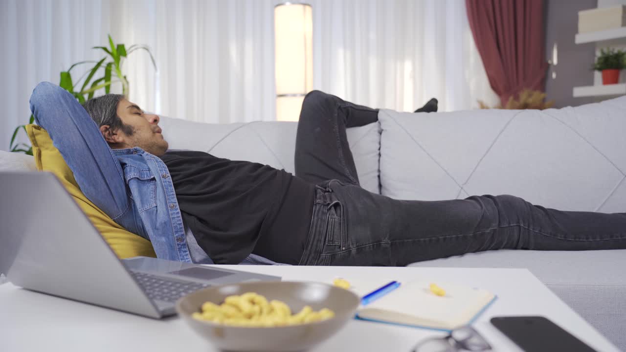 피곤한 남자가 일 끝에 집에 와서 소파에 몸을 던졌다.