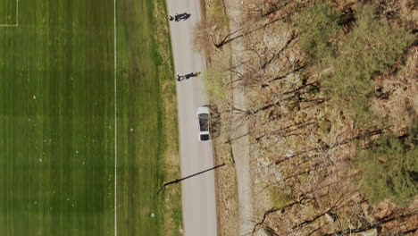 aerial tracking shot from above following white car on spring day