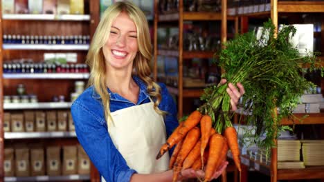 personal sonriente sosteniendo un ramo de zanahorias en la sección orgánica
