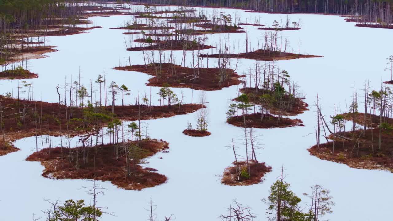 Cinematic drone shot flying above snowy Cenu bog islands during strong winds