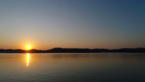 Relaxing-sunset-time-lapse-over-a-calm-lake-with-mountains-in-the-background