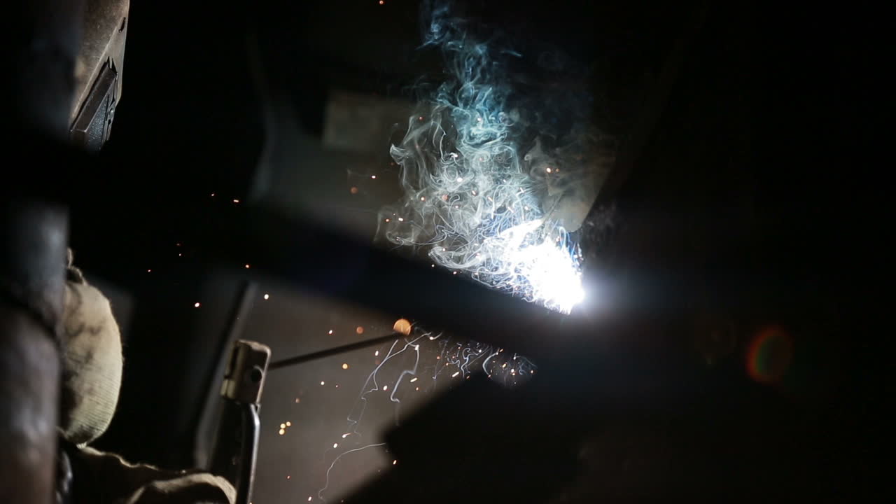 Welding sparks on production. Worker is welding production part in factory