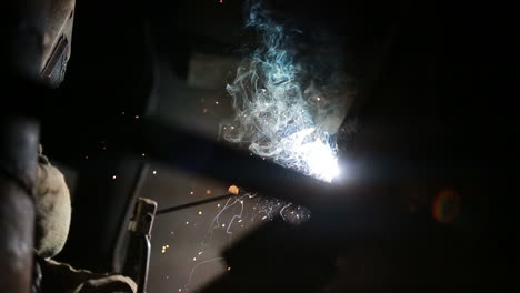 welding sparks on production. worker is welding production part in factory