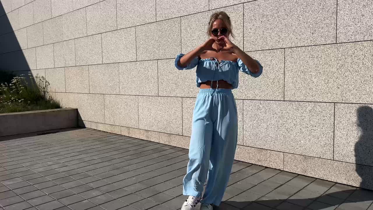 Woman in Blue Two-Piece Outfit Making Heart Shape with Hands